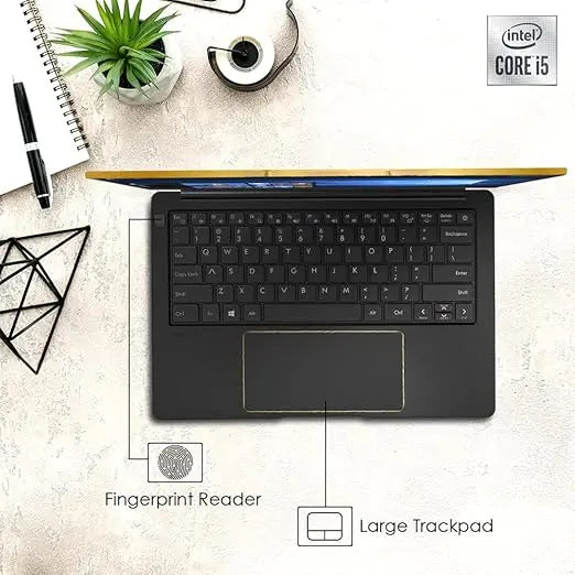 Black Avita Liber V laptop with full keyboard, large trackpad, fingerprint reader, and thin gold-colored accents on desk.